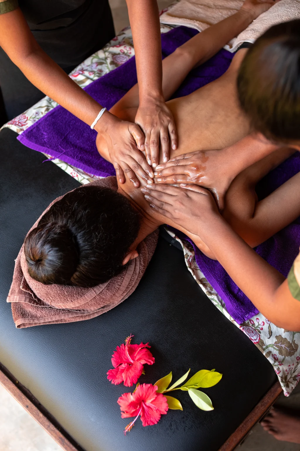 A guest receives a four-hand Ayurvedic oil massage